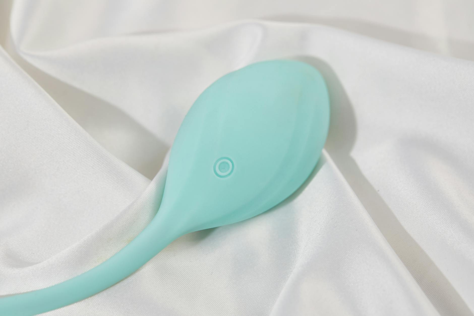 Vibrador de limón de color teal sobre tela de seda blanca, simbolizando exploración compartida en relaciones abiertas