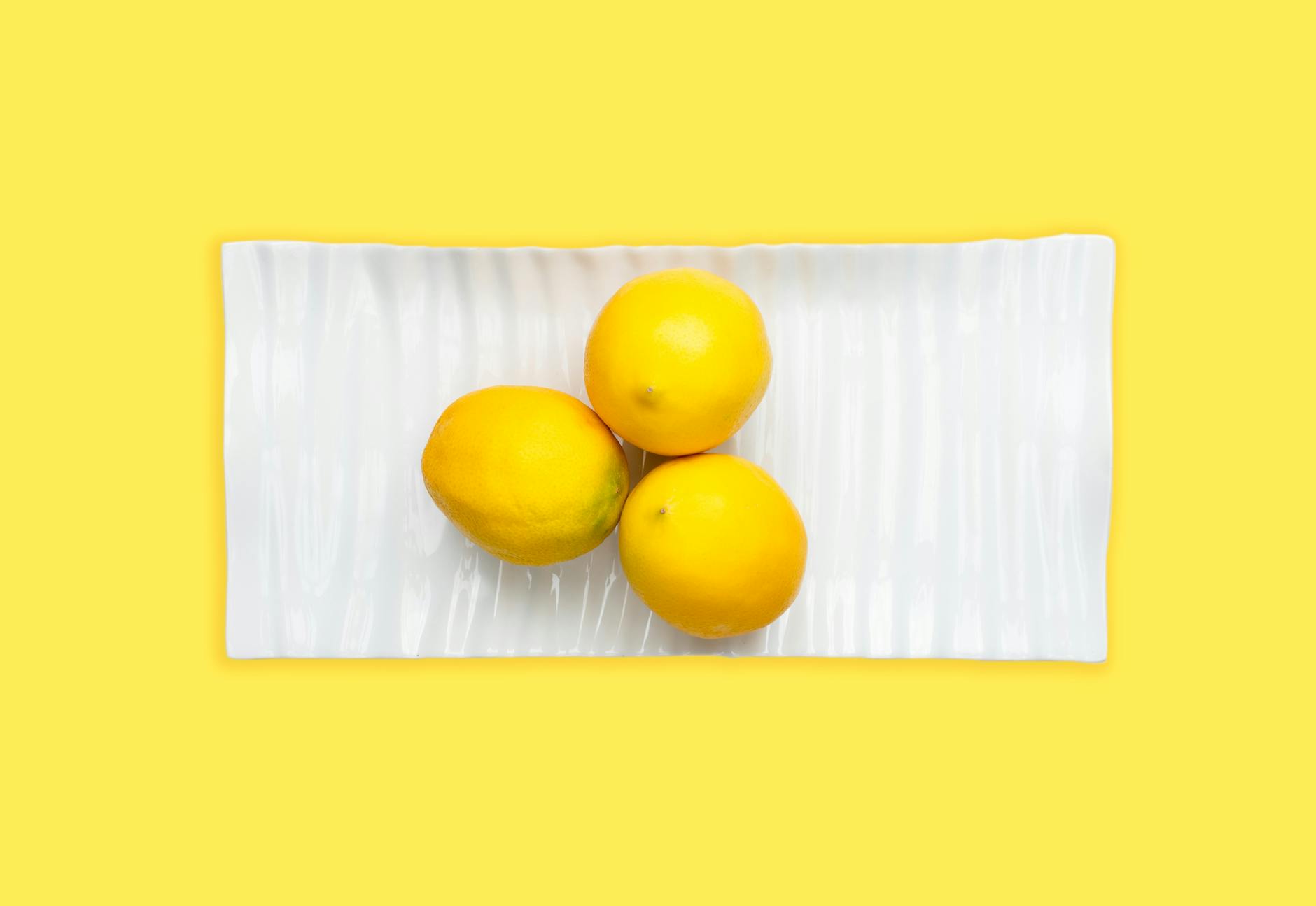 Mano sosteniendo un vibrador de succión naranja contra un fondo púrpura minimalista que muestra la sensualidad moderna
