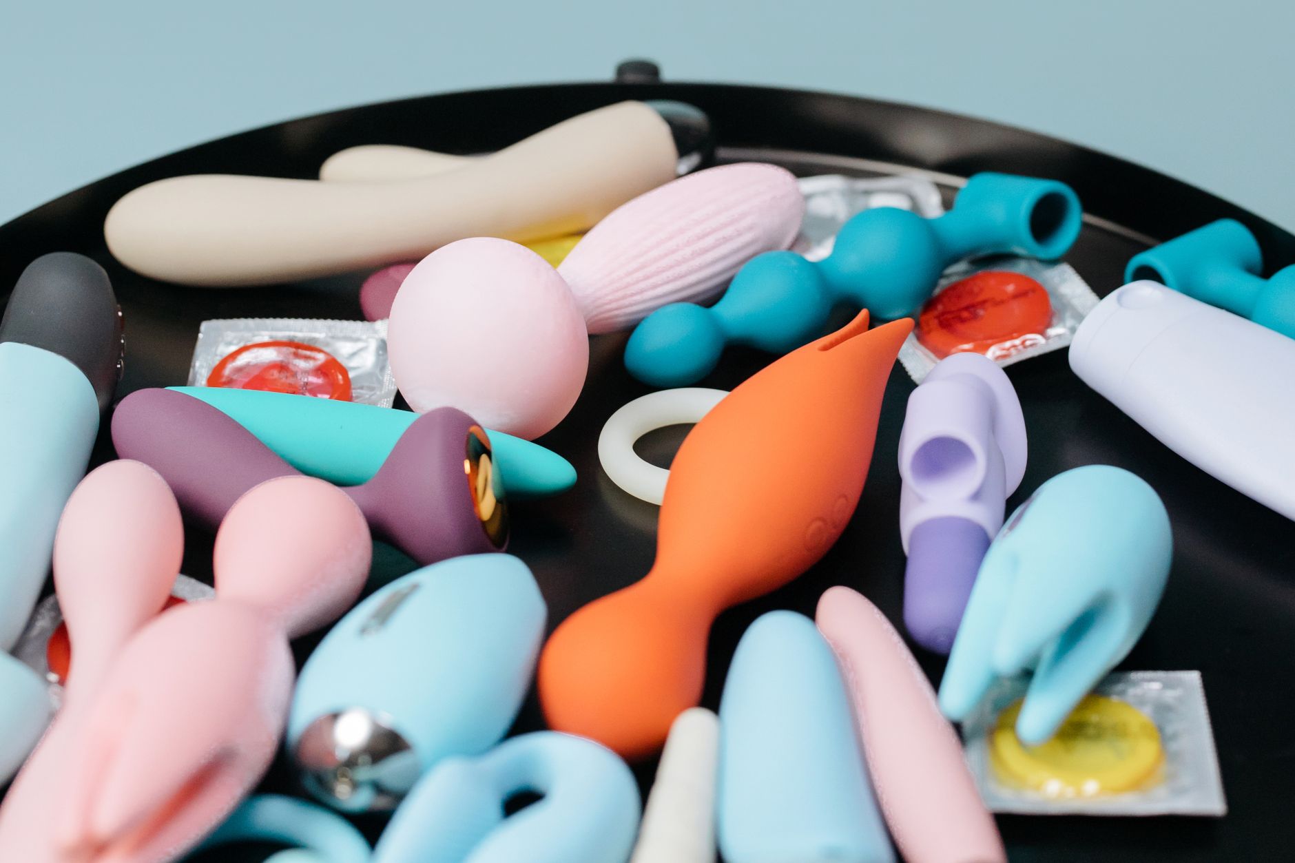 Colección vibrante de juguetes sexuales diversos en bandeja negra, mostrando formas y colores variados