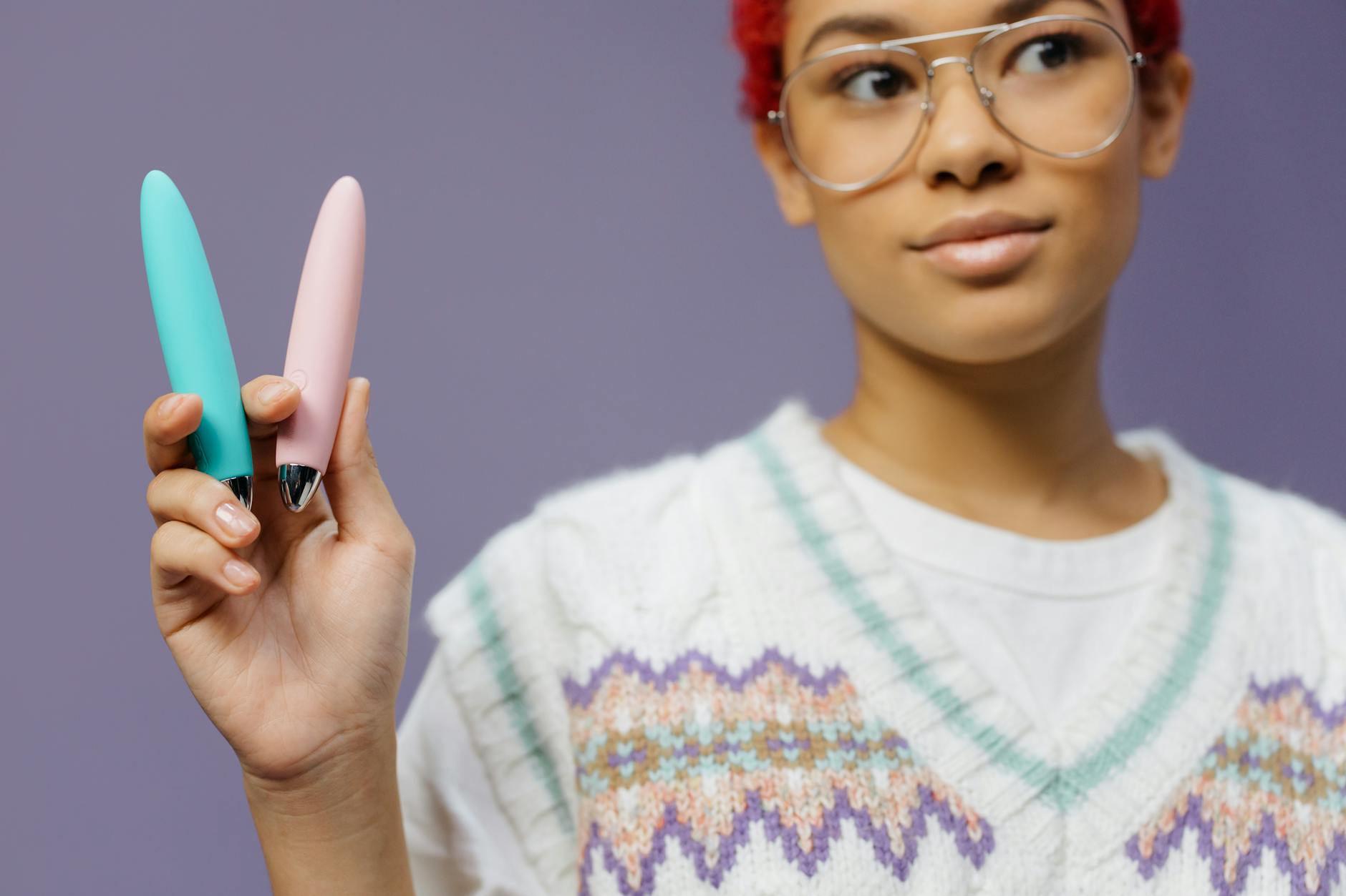 Mujer sostiene dos vibradores de silicona de colores pastel