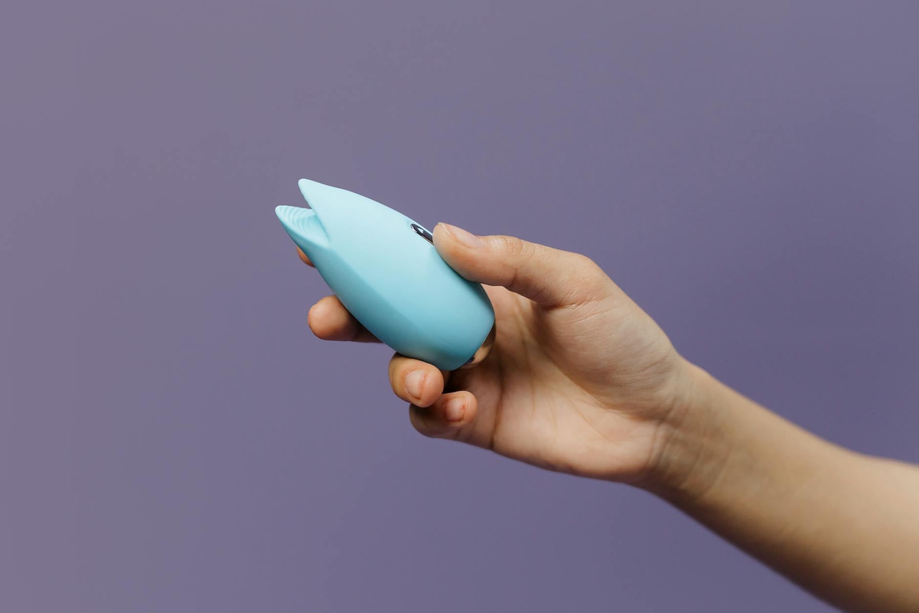 Close-up of hands holding a blue silicone clitoral vibrator, representing self-connection and rebuilding desire