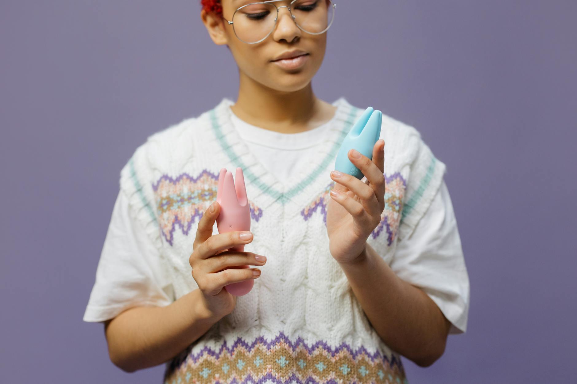 Woman holding colorful vibrators in contemplative pose, representing openness to exploring pleasure together.