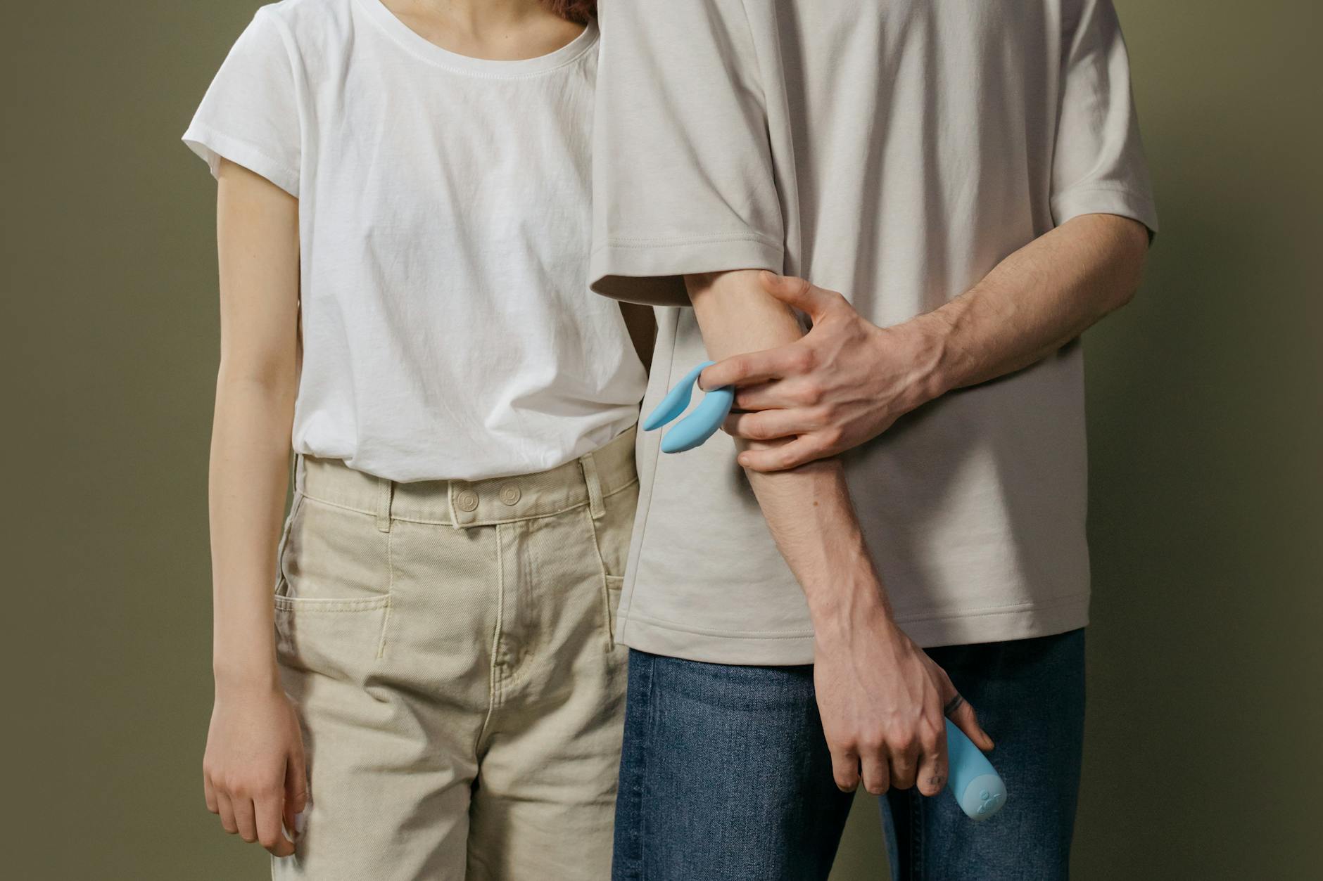 Close-up of hands holding a blue personal massager against a knitted sweater